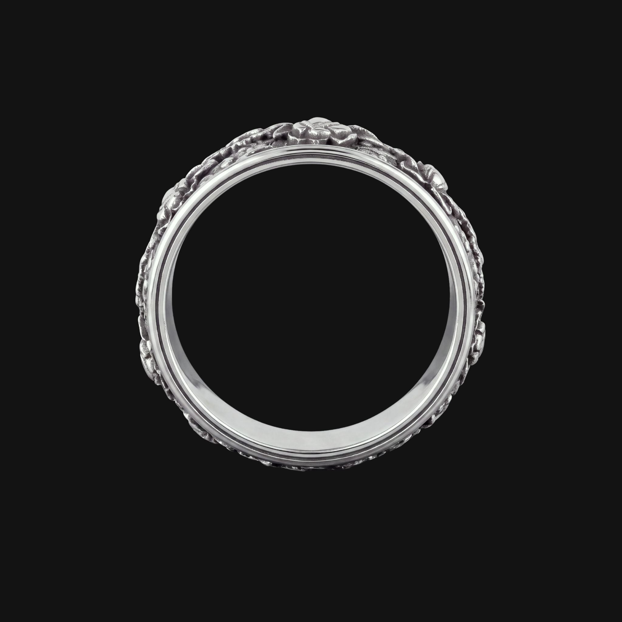 A silver ring with an ornate, textured floral border design, shown against a solid black background.