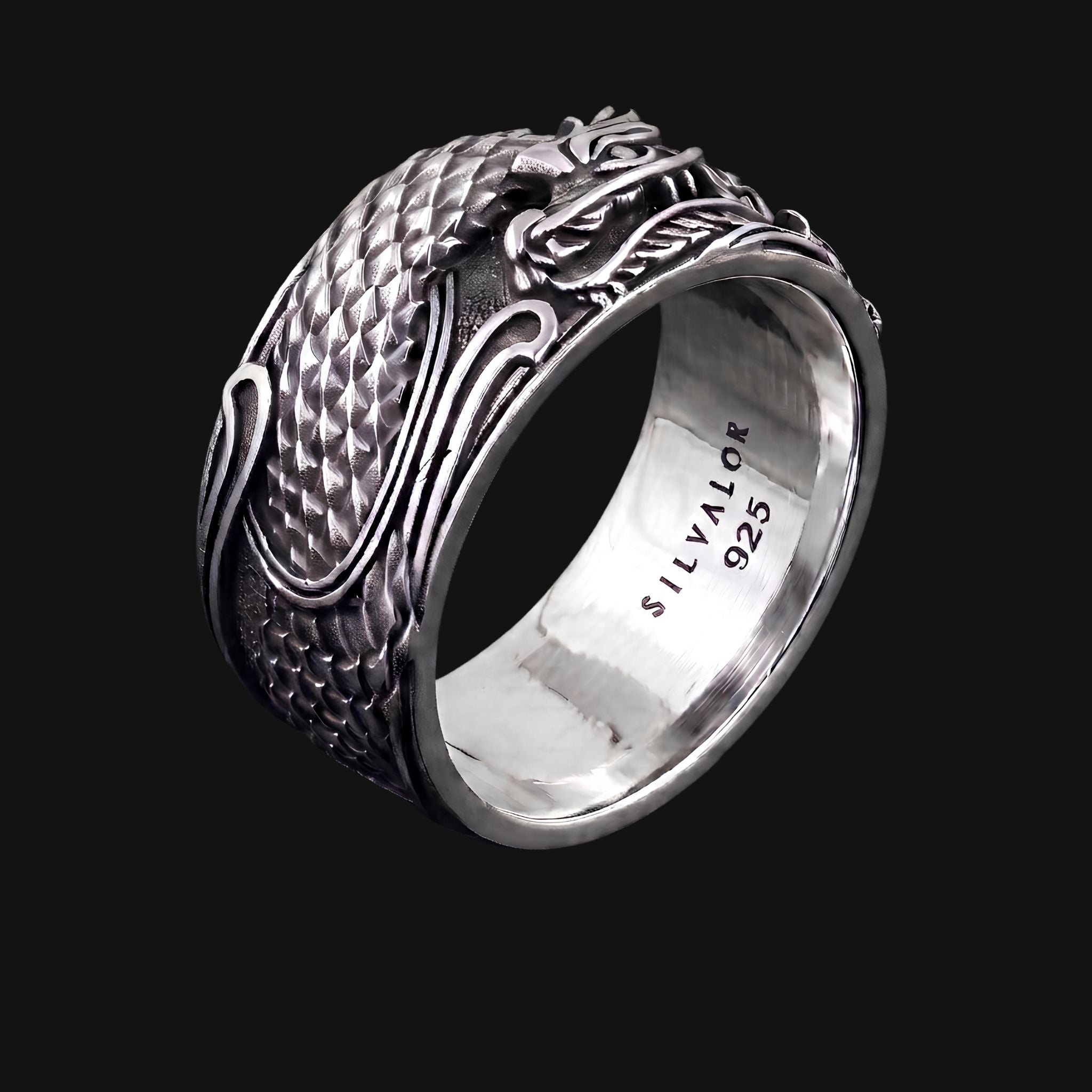 A silver dragon ring with detailed raised scales and a polished band, shown on a solid black background. The inside of the band is stamped with 'SILVALOR 925'.